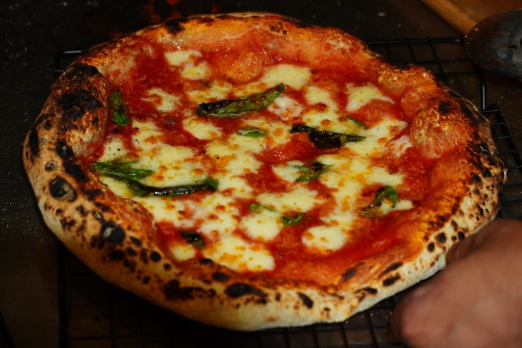 Wood-fired Margherita pizza with fresh basil on a cooling rack at Naples in a Box