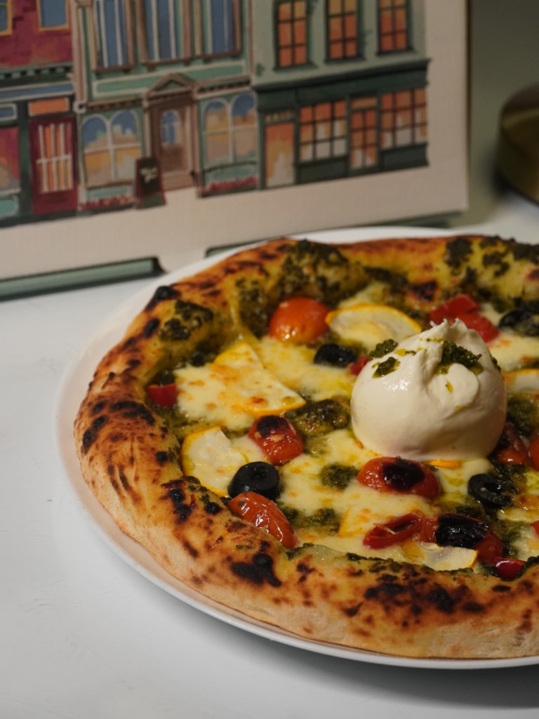 Neapolitan pizza topped with burrata, pesto, cherry tomatoes, and olives at Naples in a Box