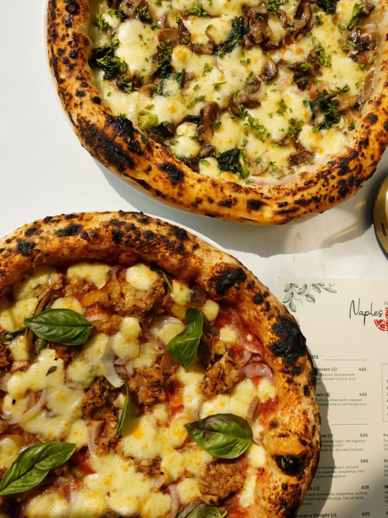 Neapolitan pizzas with the Naples in a Box printed menu showing prices and Jain options